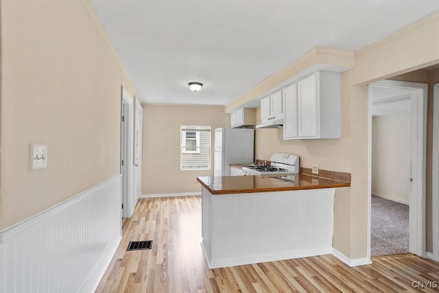 6 E 6th St, Oswego-City, NY 13126 - kitchen featuring white appliances, under cabinet range hood, white cabinetry, light wood finished floors, and a peninsula