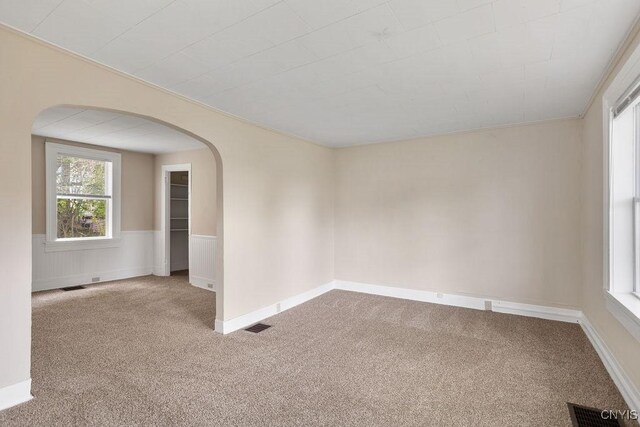 6 E 6th St, Oswego-City, NY 13126 - empty room featuring carpet floors, arched walkways, and wainscoting