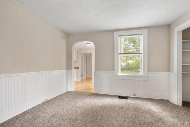 6 E 6th St, Oswego-City, NY 13126 - unfurnished room with wainscoting, carpet, arched walkways, and crown molding