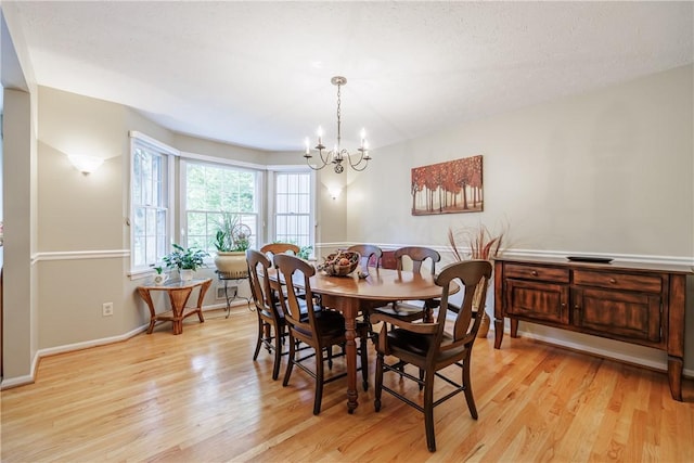 dining space featuring light wood-style floors, a chandelier, and baseboards