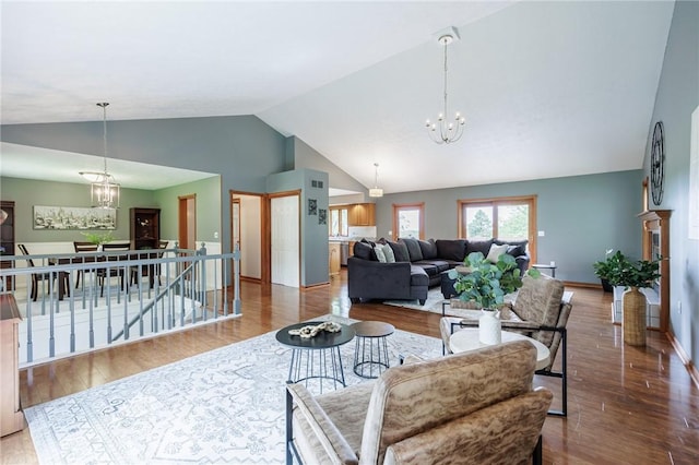 living room with a chandelier, wood finished floors, baseboards, and high vaulted ceiling