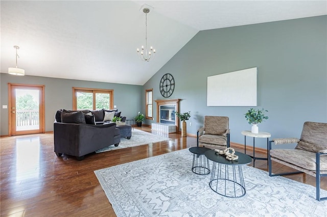 living area with wood finished floors, high vaulted ceiling, a chandelier, a glass covered fireplace, and baseboards