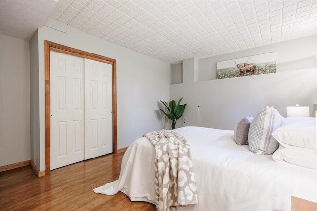 bedroom with wood finished floors, a closet, and baseboards