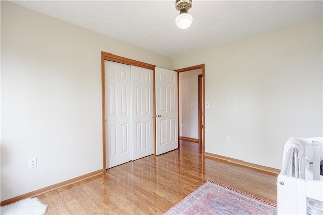 bedroom with wood finished floors, baseboards, and a closet