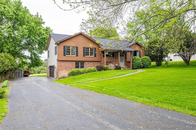 view of front facade with brick siding, a front yard, an attached garage, and driveway