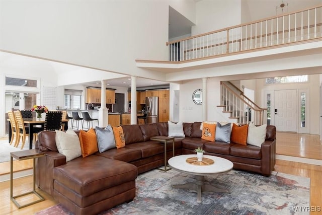 living area with a high ceiling, light wood finished floors, and stairs