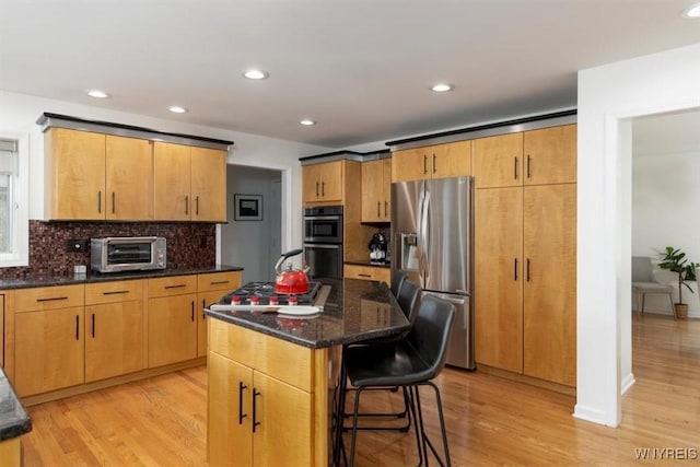 kitchen with stainless steel appliances, decorative backsplash, light wood-style floors, a kitchen bar, and recessed lighting