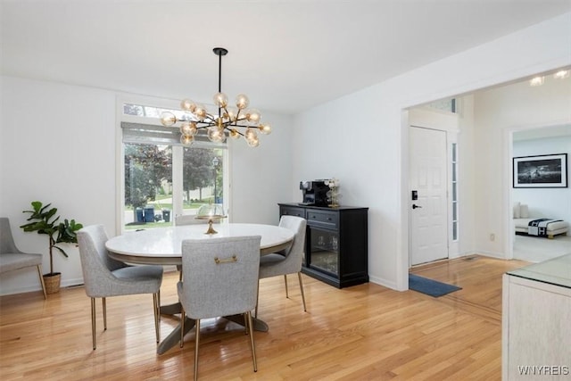 dining space with a chandelier, light wood-type flooring, and baseboards