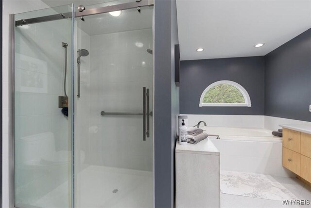 full bathroom featuring a stall shower, a garden tub, recessed lighting, and vanity