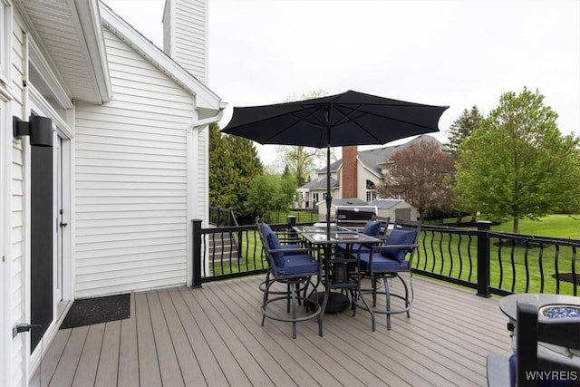 wooden deck with outdoor dining area, a lawn, and grilling area