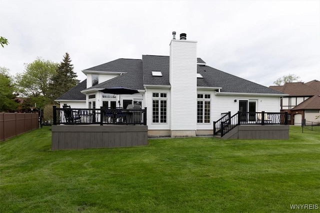 rear view of property featuring a wooden deck, a chimney, and roof with shingles