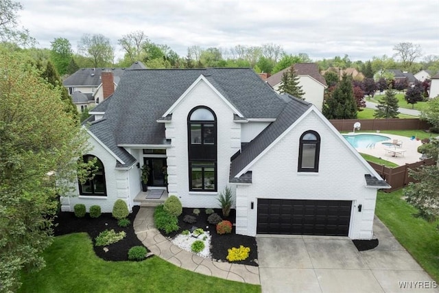 view of front of house featuring brick siding, roof with shingles, and a garage