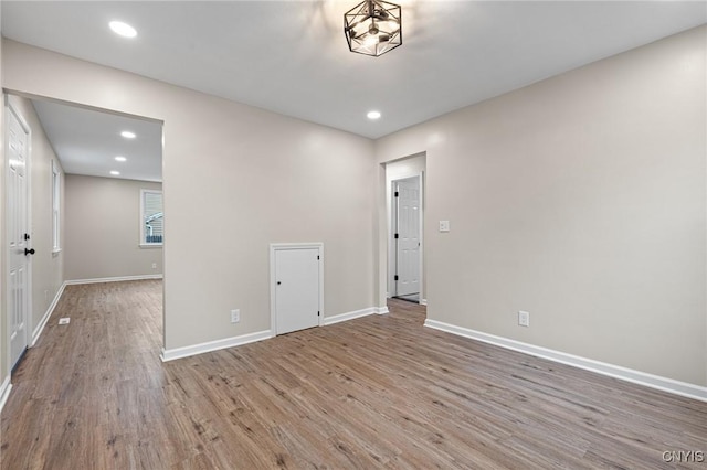 spare room featuring wood finished floors, baseboards, and recessed lighting