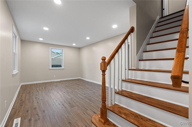staircase with wood finished floors, recessed lighting, and baseboards