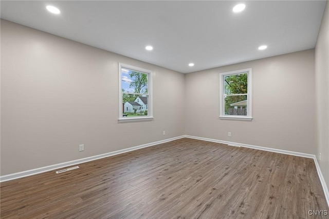 spare room with wood finished floors, baseboards, and recessed lighting