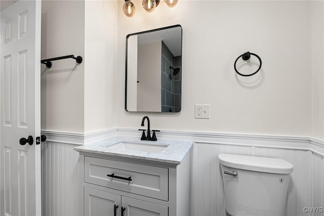bathroom with a wainscoted wall, vanity, and toilet
