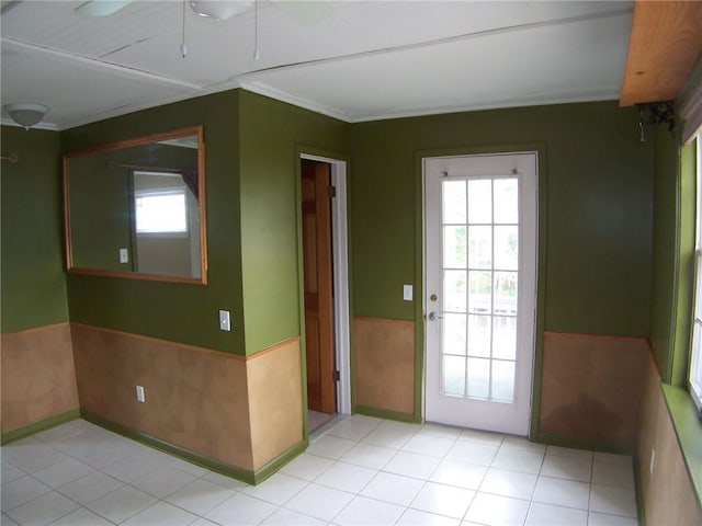 unfurnished room featuring wainscoting, crown molding, light tile patterned floors, and ceiling fan