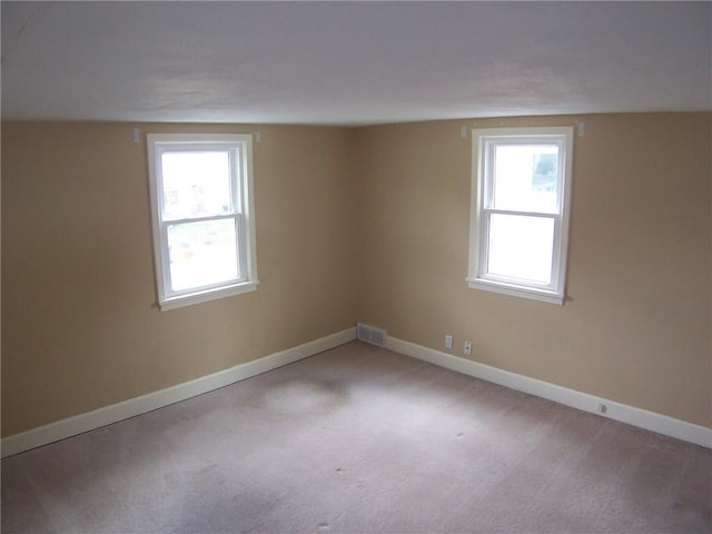 empty room with plenty of natural light, baseboards, and carpet flooring