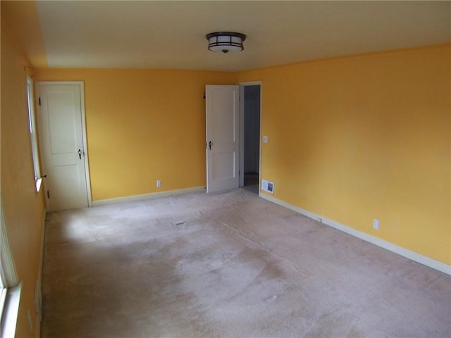 spare room featuring baseboards and light carpet