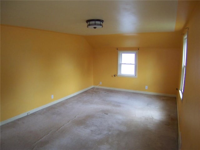 spare room featuring carpet flooring, baseboards, and lofted ceiling