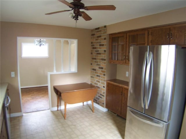 kitchen with freestanding refrigerator, light floors, brown cabinetry, a ceiling fan, and baseboards
