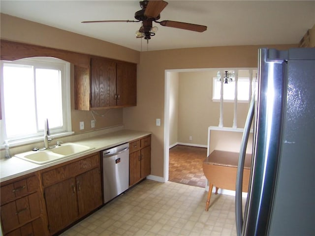 kitchen with appliances with stainless steel finishes, a sink, light floors, and plenty of natural light