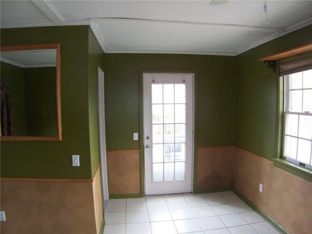 doorway featuring wainscoting, ornamental molding, and light tile patterned floors