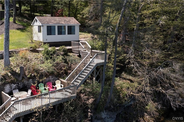 back of house featuring stairs, a deck, an outdoor structure, and a view of trees