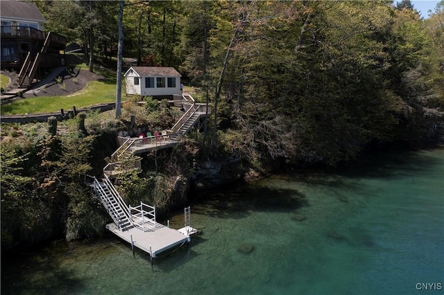 aerial view of property and surrounding area with a heavily wooded area and a nearby body of water