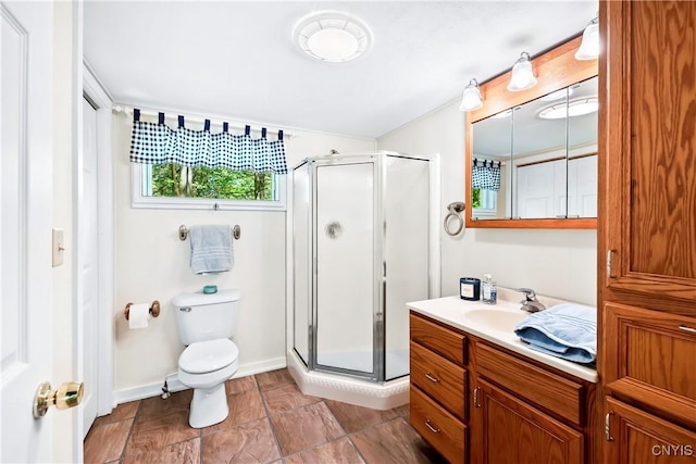 bathroom with vanity, a shower stall, toilet, and baseboards