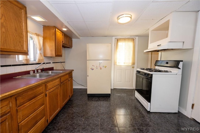 2282 Seneca St, Buffalo, NY 14210 - kitchen featuring range with gas stovetop, freestanding refrigerator, a sink, brown cabinetry, and decorative backsplash