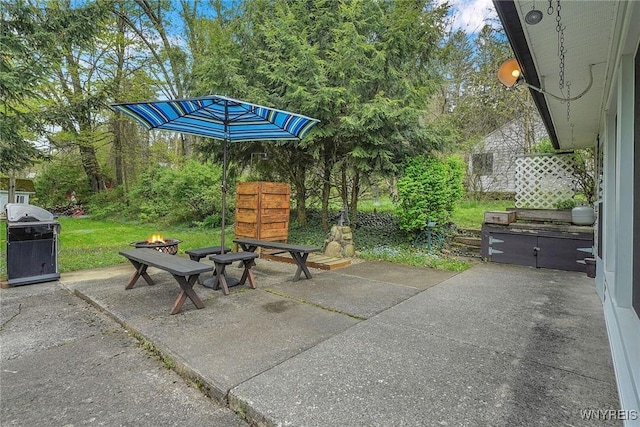view of patio / terrace with a fire pit and view of wooded area