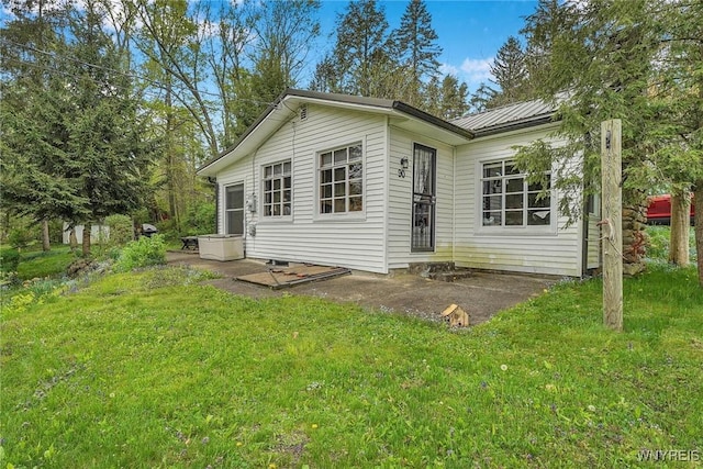 back of house featuring a yard and metal roof