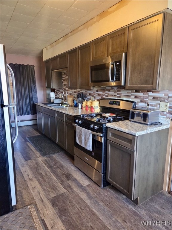 11343 Slade Rd, Ridgeway, NY 14103 - kitchen featuring stainless steel appliances, a sink, dark wood-style floors, decorative backsplash, and light stone countertops