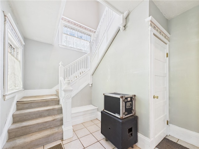 stairs featuring healthy amount of natural light, tile patterned flooring, and baseboards