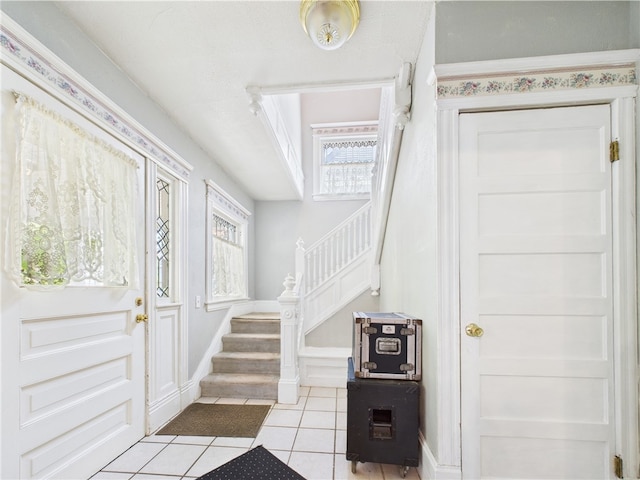 entryway featuring stairway, light tile patterned flooring, and baseboards