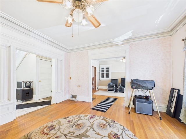 sitting room featuring a ceiling fan, crown molding, wood finished floors, and baseboards