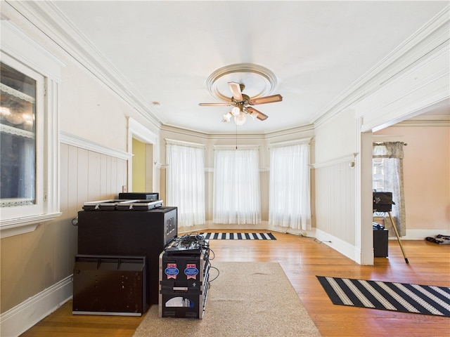 office space with a ceiling fan, wood finished floors, crown molding, and baseboards