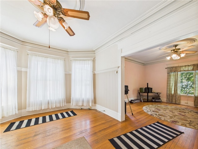living area featuring ceiling fan, hardwood / wood-style flooring, ornamental molding, and baseboards