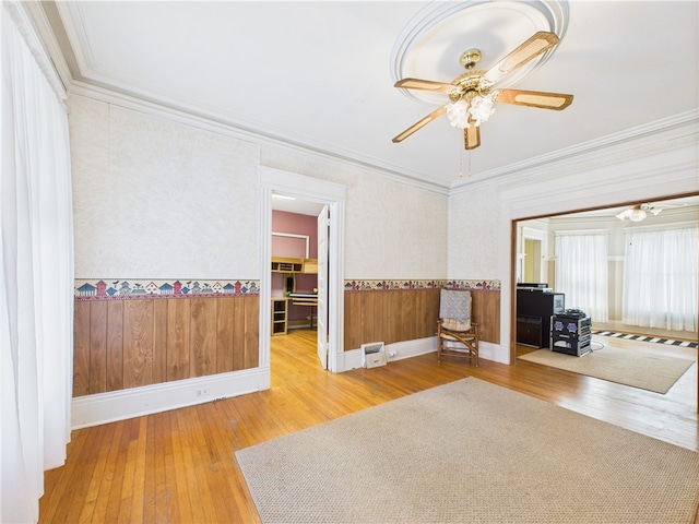spare room featuring hardwood / wood-style flooring, crown molding, a ceiling fan, and baseboards