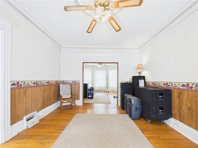 sitting room featuring a ceiling fan, ornamental molding, wood finished floors, and a wainscoted wall