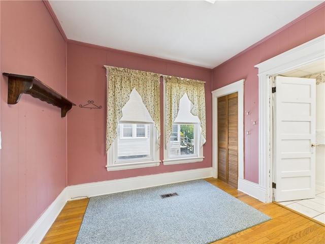 empty room with wood finished floors, baseboards, and crown molding