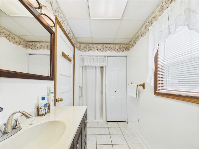 bathroom featuring a paneled ceiling, tile patterned floors, vanity, and baseboards