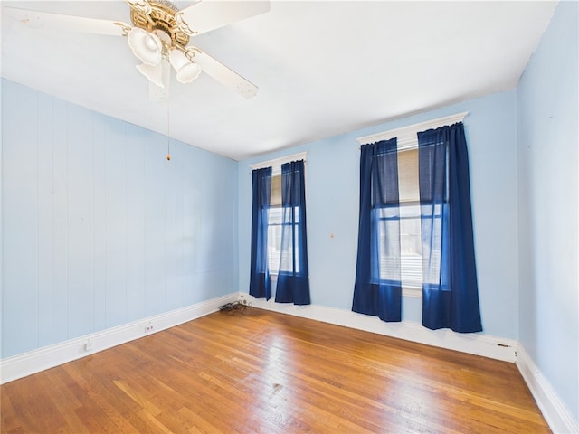 empty room with wood finished floors, baseboards, and a ceiling fan