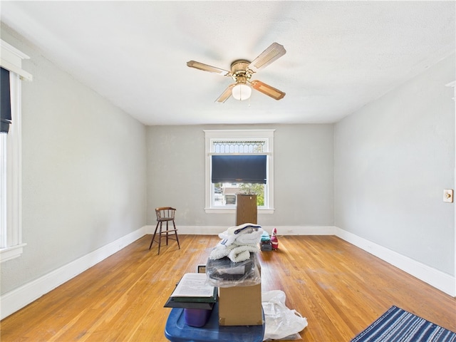 sitting room with a ceiling fan, wood finished floors, and baseboards