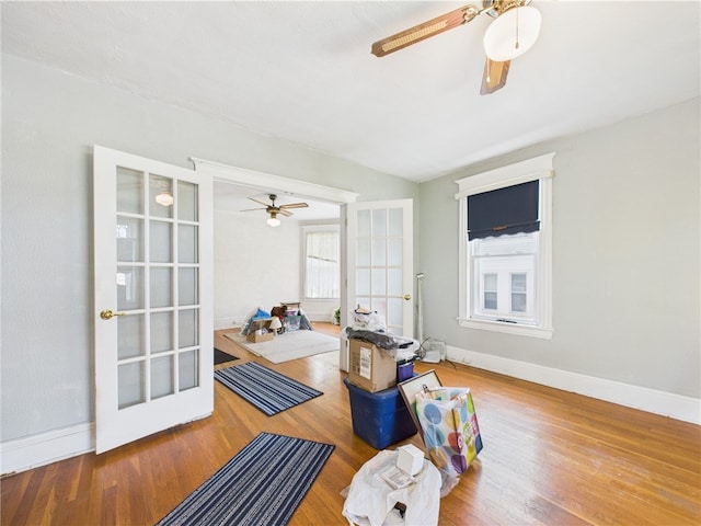 interior space featuring ceiling fan, baseboards, healthy amount of natural light, and wood finished floors