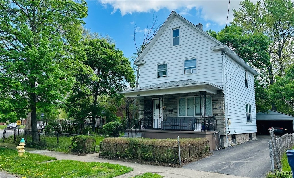 2817 10th St, Niagara Falls, NY 14305 - american foursquare style home featuring covered porch, a fenced front yard, an outbuilding, a chimney, and stone siding