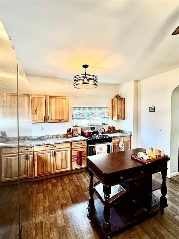 426 Loder St, Barton, NY 14892 - kitchen with gas range, dark wood-style floors, arched walkways, and brown cabinets