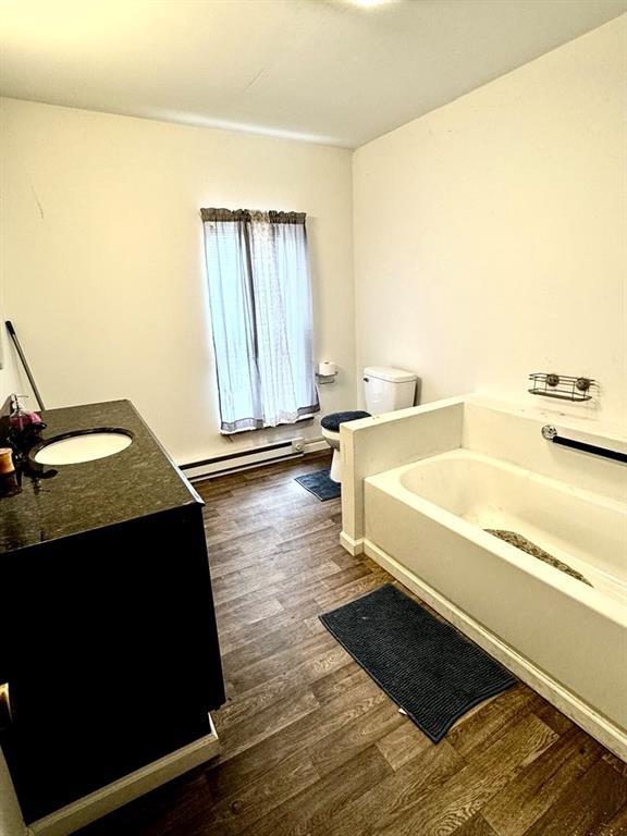 426 Loder St, Barton, NY 14892 - full bath featuring baseboard heating, wood finished floors, toilet, a garden tub, and vanity