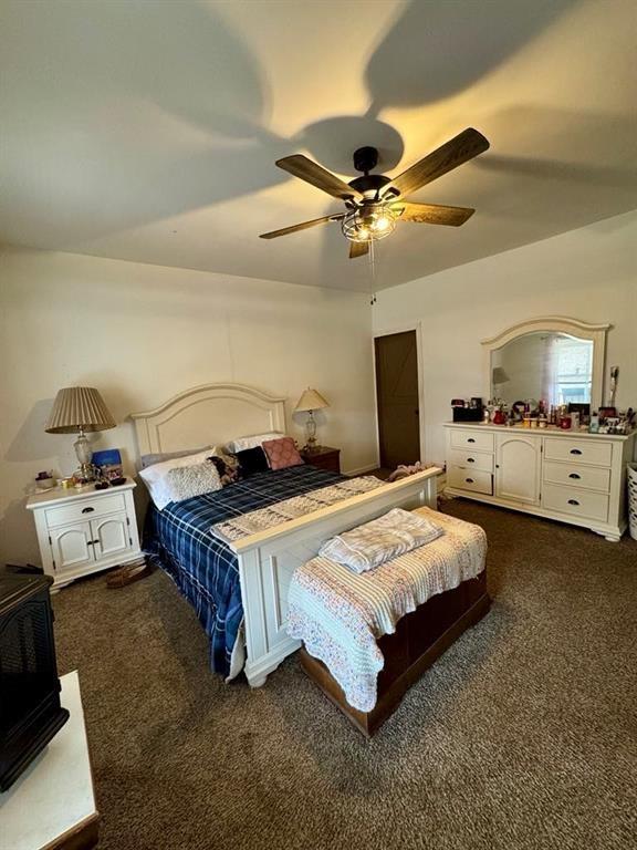 426 Loder St, Barton, NY 14892 - bedroom with dark colored carpet, a ceiling fan, and a wood stove